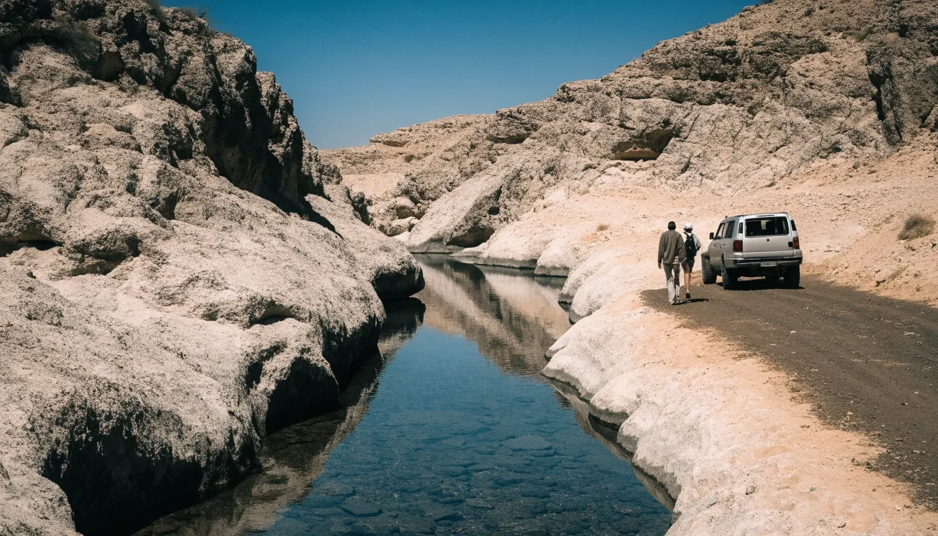 Wadi în Oman cu apă mică între pereți de stâncă, mașină parcată pe traseu