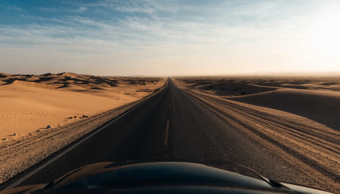 Șosea deșertică lungă și dreaptă în Oman, văzută de la nivelul capotei, la ora aurie